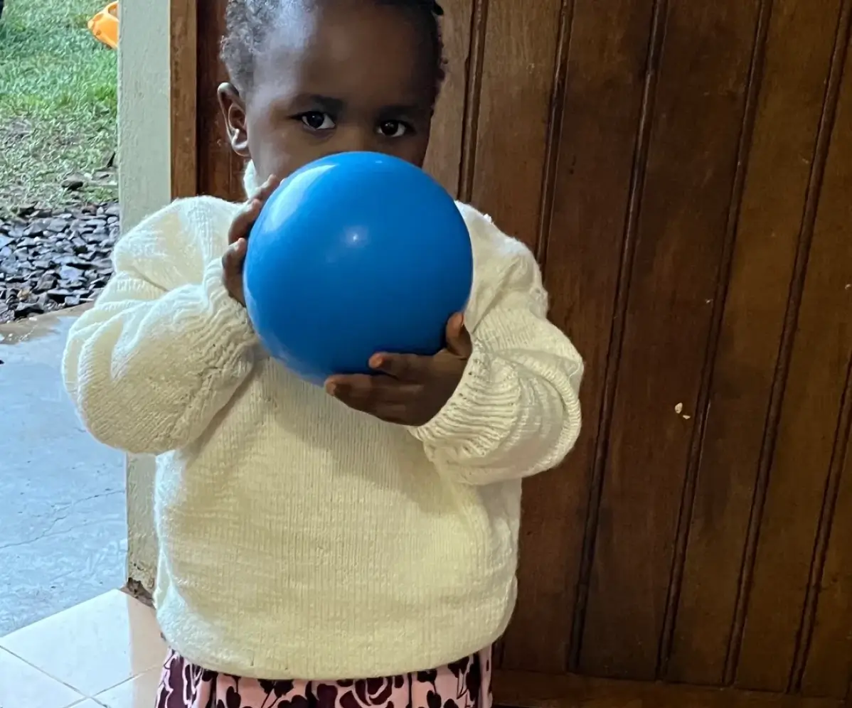 Child holding bright blue ball indoors