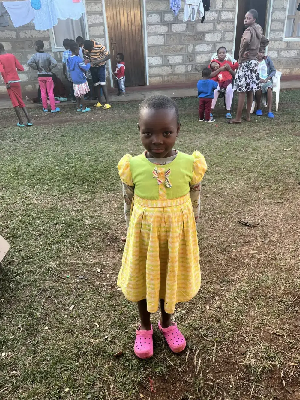 Child in yellow dress standing outside.