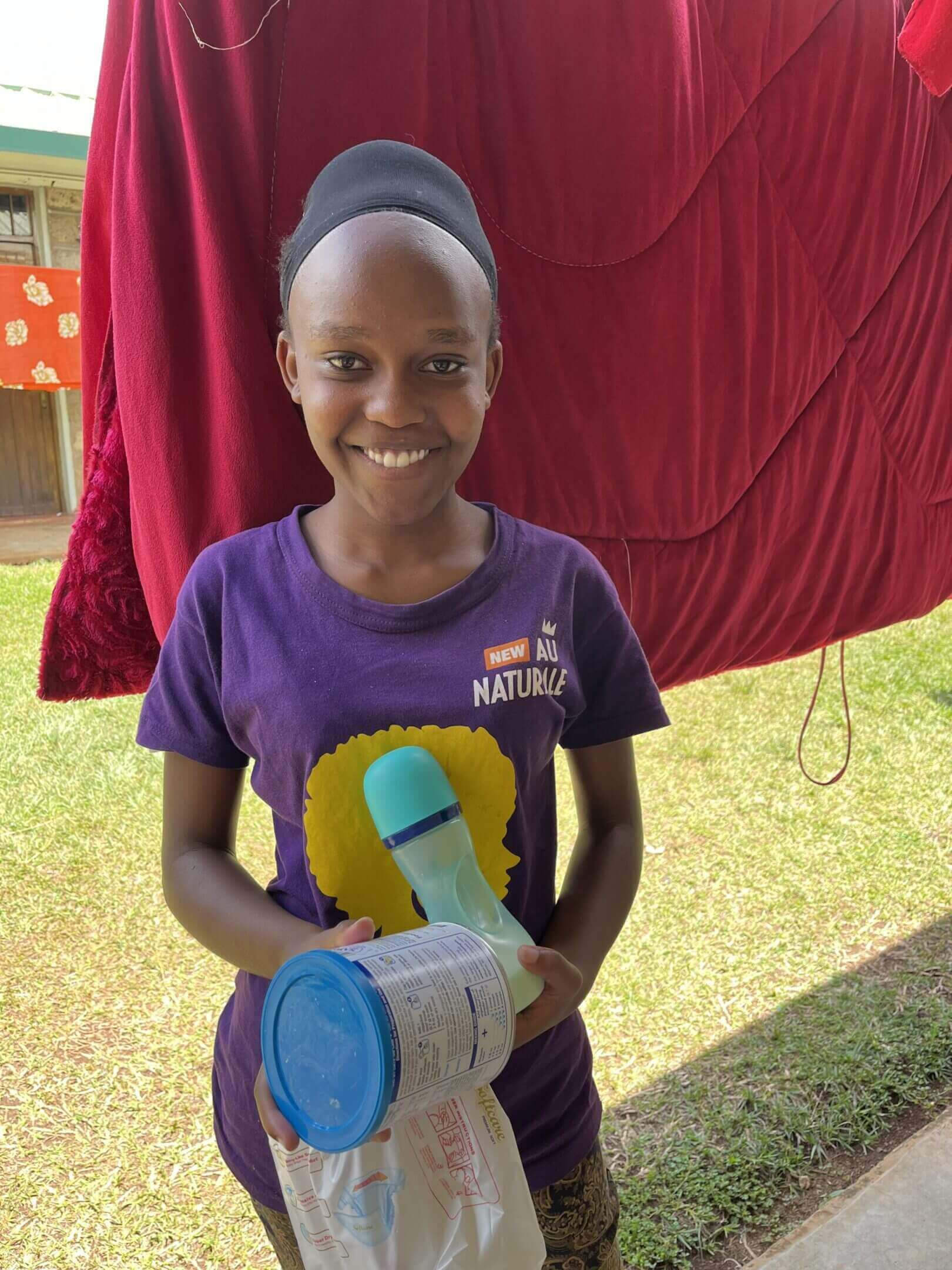 Girl smiling, holding container and bottle.