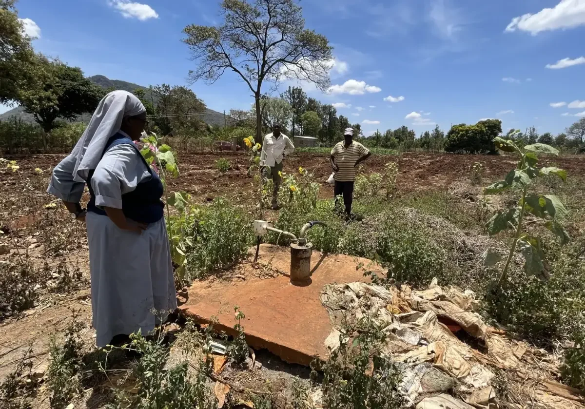 People standing near a field pump.