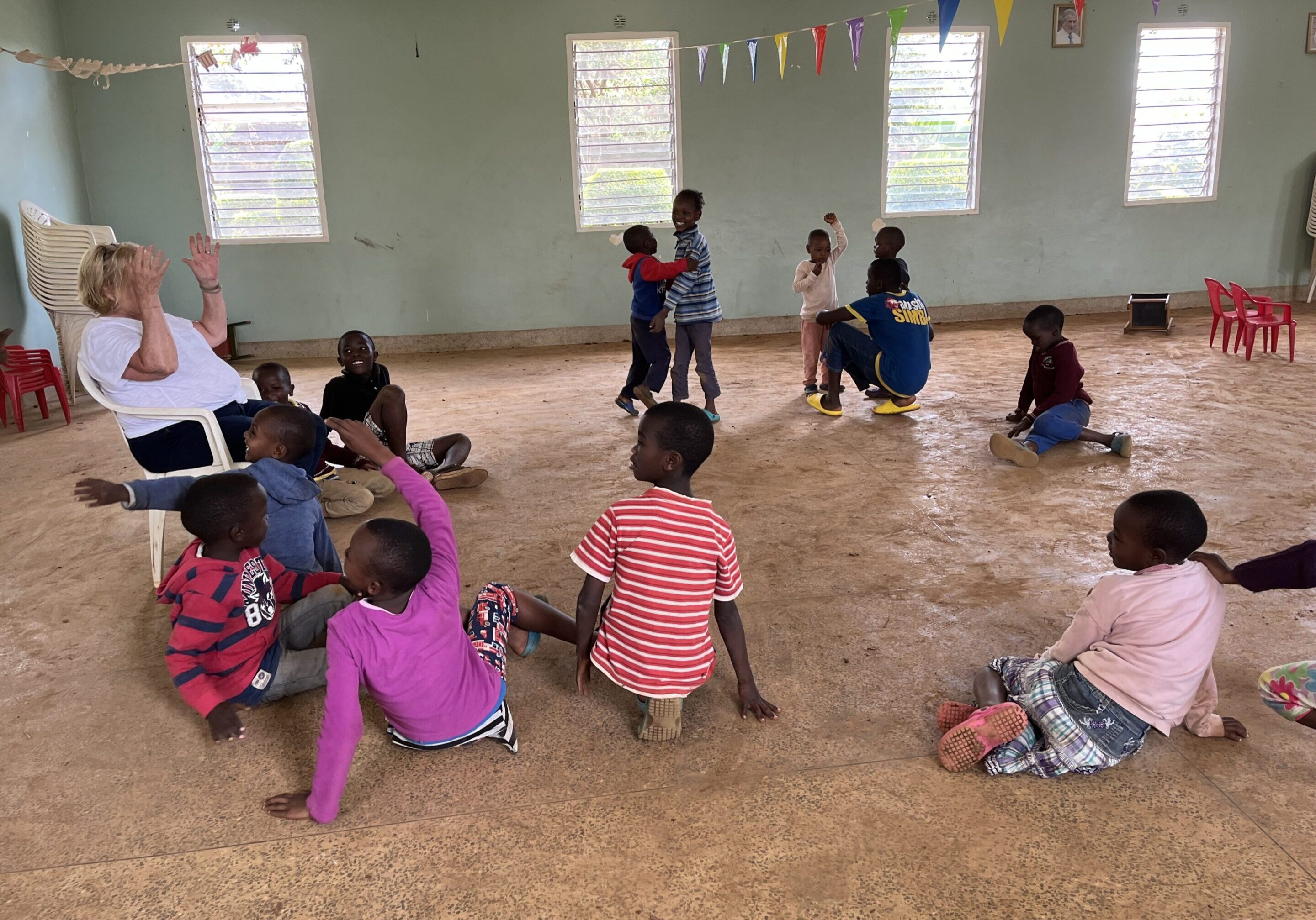 Children sitting on the floor in a classroom, engaged in activities.